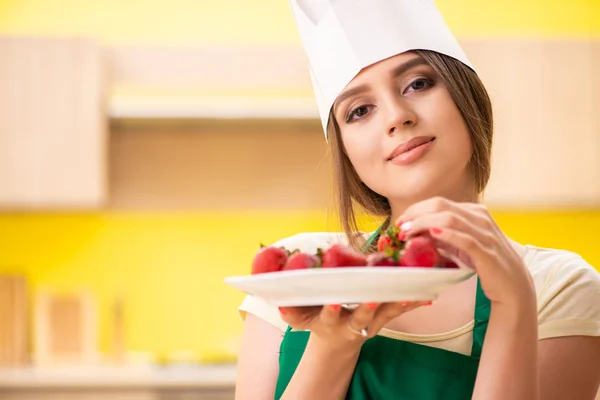 Jonge vrouwelijke kok die aardbeien eet — Stockfoto