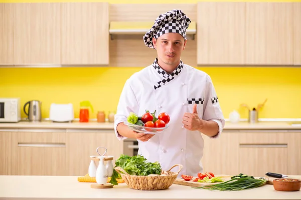 Jovem cozinheiro profissional preparando salada na cozinha — Fotografia de Stock