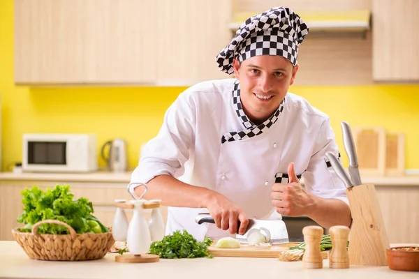 Jovem cozinheiro profissional preparando salada na cozinha — Fotografia de Stock