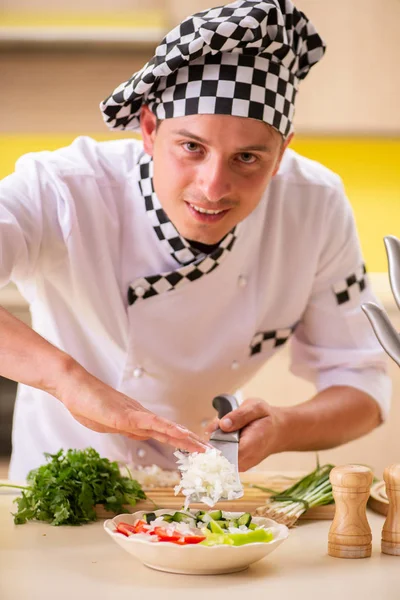 Joven cocinero profesional preparando ensalada en la cocina — Foto de Stock