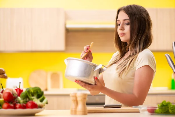 Jonge vrouw koken soep in keuken thuis — Stockfoto