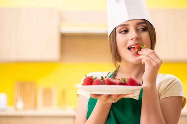 Mladá kuchařka jí jahody — Stock fotografie