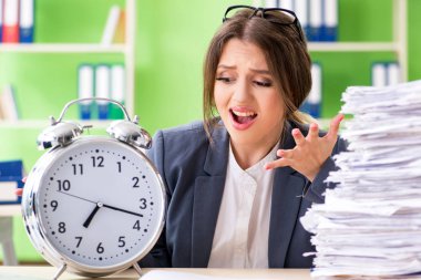 Young female employee very busy with ongoing paperwork in time m clipart