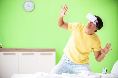 Yatak odasında sanal gözlüklü genç adam. 