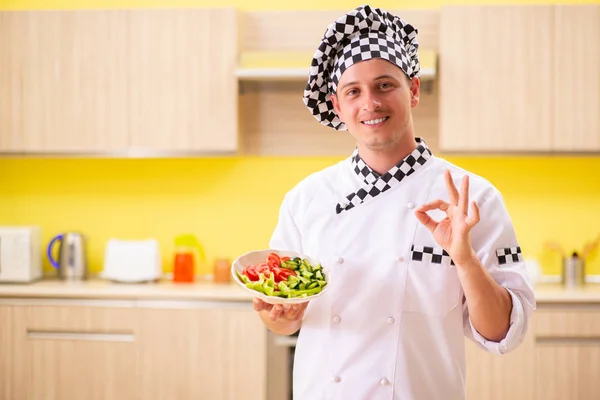 Jovem cozinheiro profissional preparando salada na cozinha — Fotografia de Stock