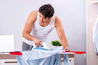 Genç adam yatak odasında ütü yapıyor. 