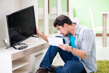 Genç adam evde televizyon tamir ediyor. 