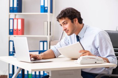 Genç yakışıklı işadamı ofiste çalışıyor.