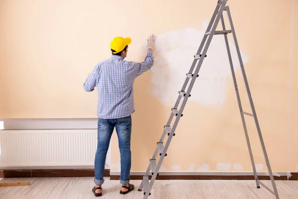 Young contractor sanding wall down with sandpaper — Stock Photo, Image