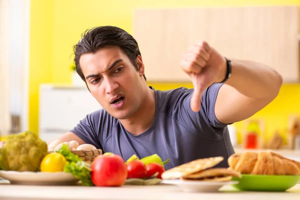 Hombre que tiene difícil elección entre la comida sana y no saludable —  Fotos de Stock