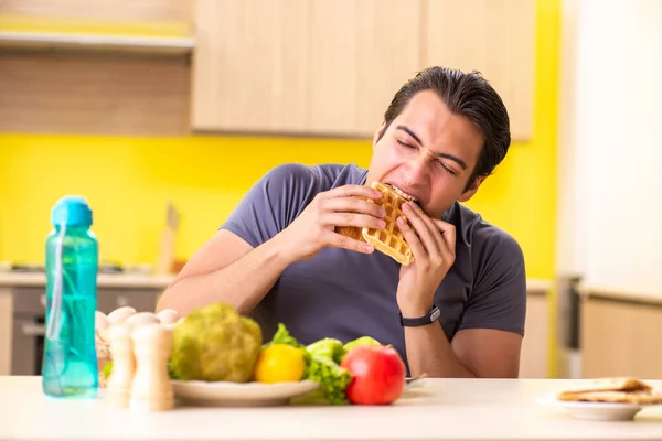 Homem tendo escolha difícil entre alimentos saudáveis e não saudáveis — Fotografia de Stock