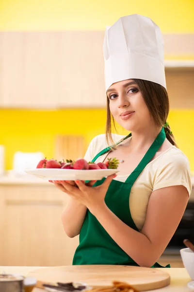 Jovem cozinheira comendo morangos — Fotografia de Stock