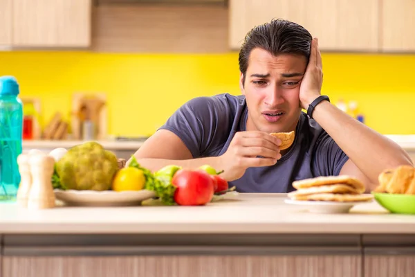 Uomo che ha una scelta difficile tra cibo sano e malsano — Foto Stock