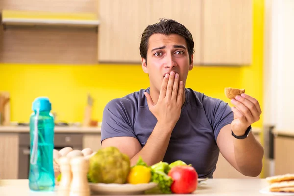 Hombre que tiene difícil elección entre la comida sana y no saludable —  Fotos de Stock