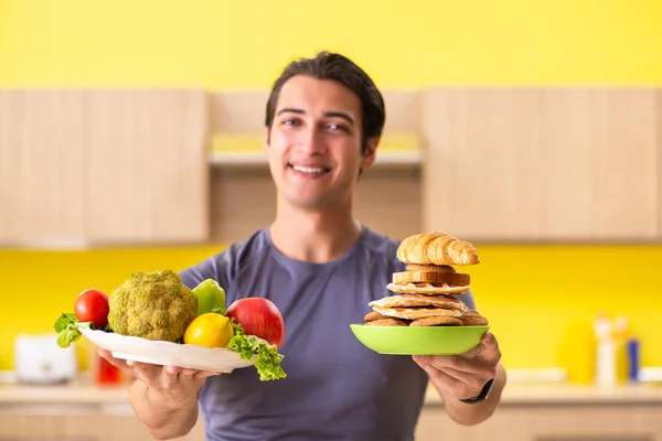 Hombre que tiene difícil elección entre la comida sana y no saludable — Foto de Stock