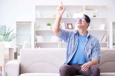 Evde sanal gerçeklik gözlüklü bir adam oynuyor.