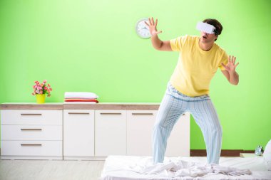 Yatak odasında sanal gözlüklü genç adam. 