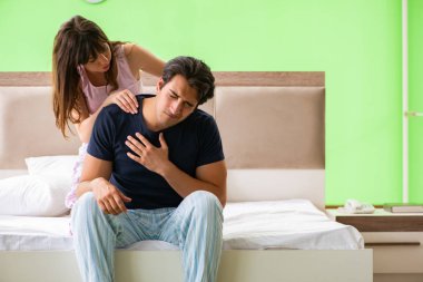 Yatak odasında kocasına masaj yapan bir kadın. 