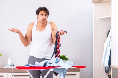 Genç adam yatak odasında ütü yapıyor. 