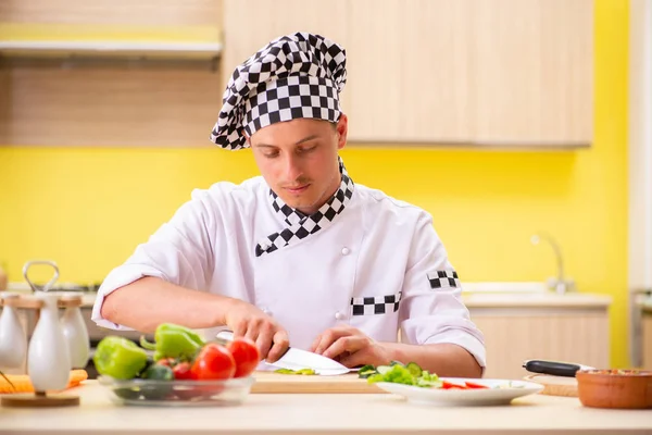 Joven cocinero profesional preparando ensalada en la cocina — Foto de Stock