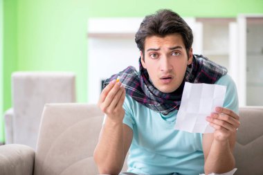 Evde hastalıktan muzdarip genç yakışıklı bir adam. 