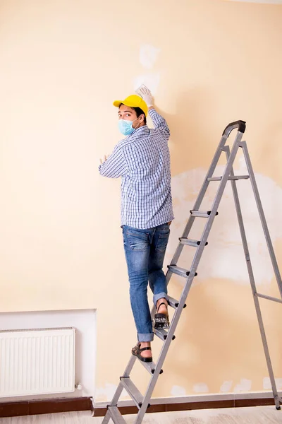 Young contractor sanding wall down with sandpaper — Stock Photo, Image