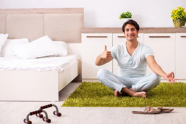 Молодий чоловік робить йогу в спальні — стокове фото