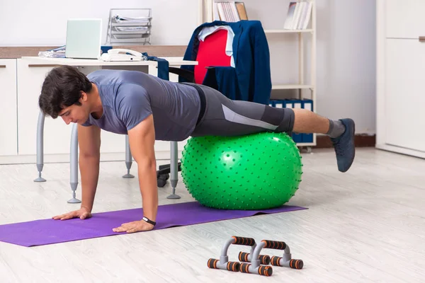 Young male employee exercising in the office — Stock Photo, Image