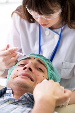 Estetik cerrah insan yüzü ameliyatına hazırlanıyor.