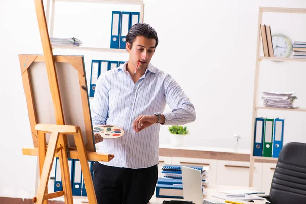 Joven empleado guapo disfrutando de la pintura en la oficina — Foto de Stock