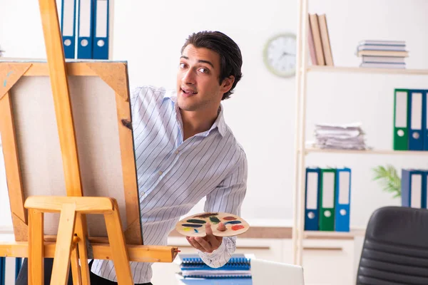Ung snygg anställd njuter av målning på kontoret — Stockfoto