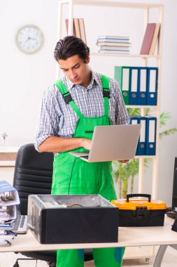Ofiste bozuk bilgisayarı tamir eden genç bir mühendis. 