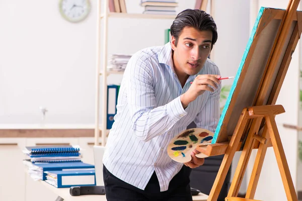 Jovem e bonito funcionário desfrutando de pintura no escritório — Fotografia de Stock