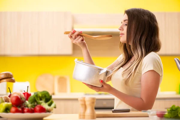 Jonge vrouw koken soep in keuken thuis — Stockfoto