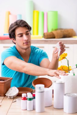 Sınıfta çömlek dekorasyonu yapan genç bir adam.