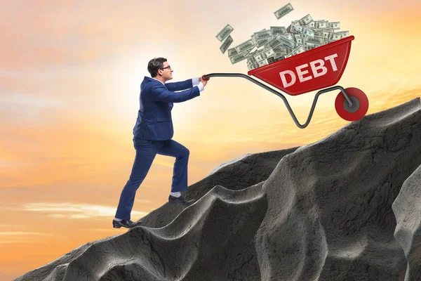 Uomo d'affari spingendo carriola in salita nel concetto di prestito del debito — Foto Stock