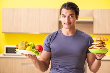 Sağlıklı ve sağlıksız yemek arasında zor bir seçim yapan bir adam.