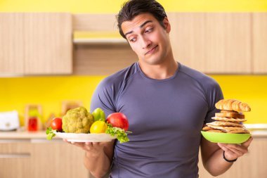 Sağlıklı ve sağlıksız yemek arasında zor bir seçim yapan bir adam.