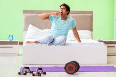 Pijamalı genç adam sabah egzersizi yapıyor. 