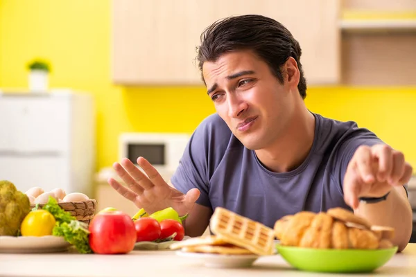 Hombre que tiene difícil elección entre la comida sana y no saludable —  Fotos de Stock