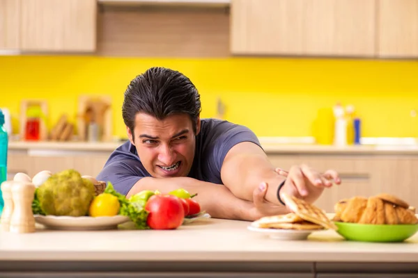 Hombre que tiene difícil elección entre la comida sana y no saludable — Foto de Stock