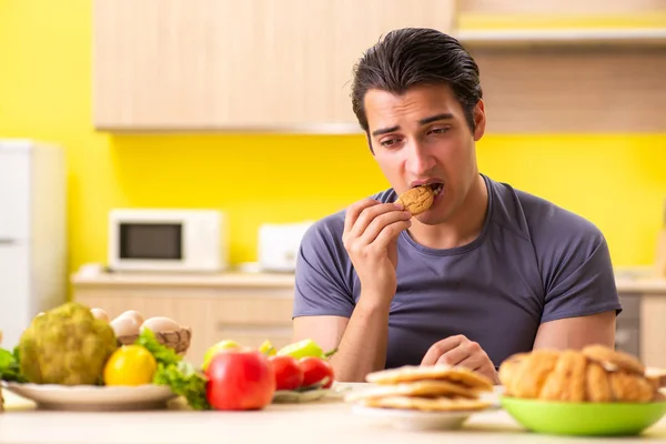 Man having hard choice between healthy and unhealthy food