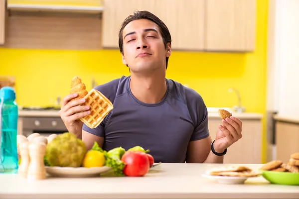 Hombre que tiene difícil elección entre la comida sana y no saludable —  Fotos de Stock