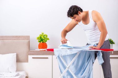 Genç adam yatak odasında ütü yapıyor. 