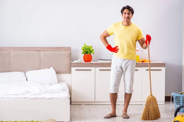 Jonge knappe man schoonmaken in de slaapkamer — Stockfoto