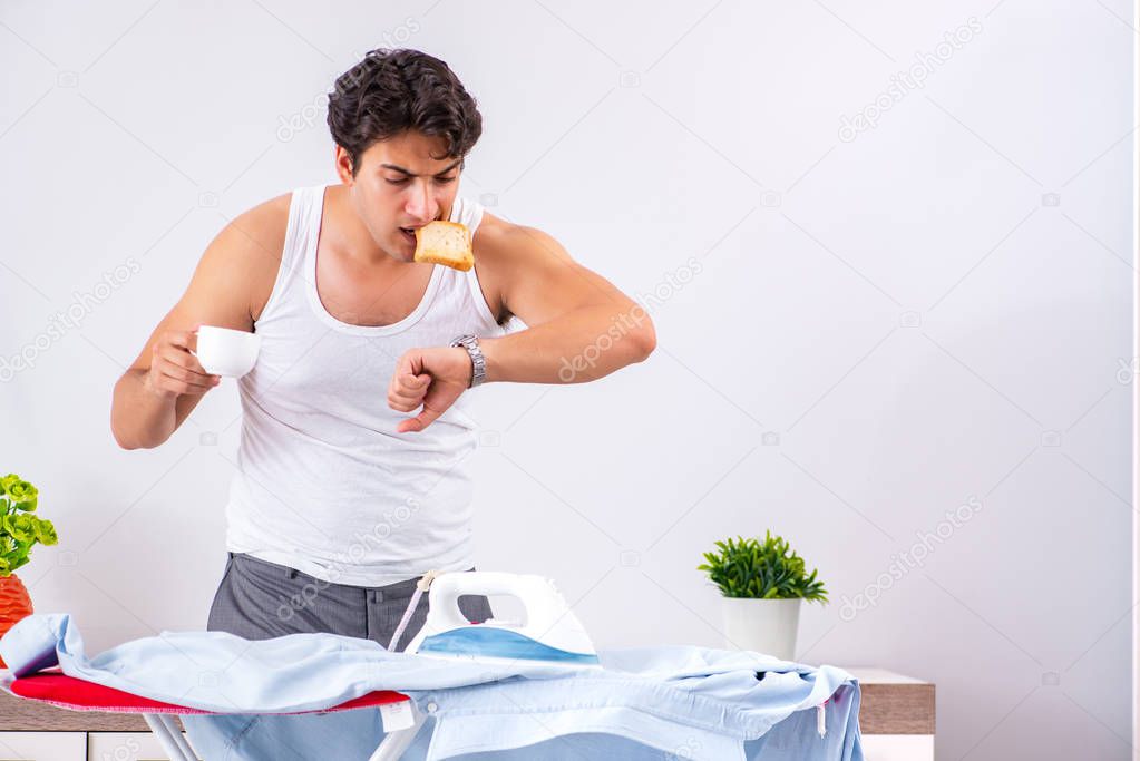 Young man ironing in the bedroom 