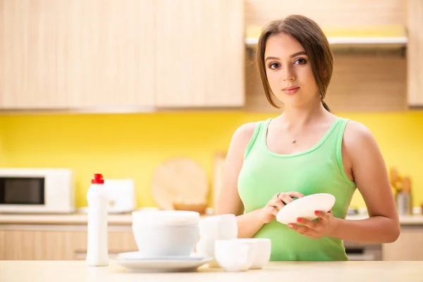 Młoda kobieta sprzątanie i mycie naczyń w kuchni — Zdjęcie stockowe