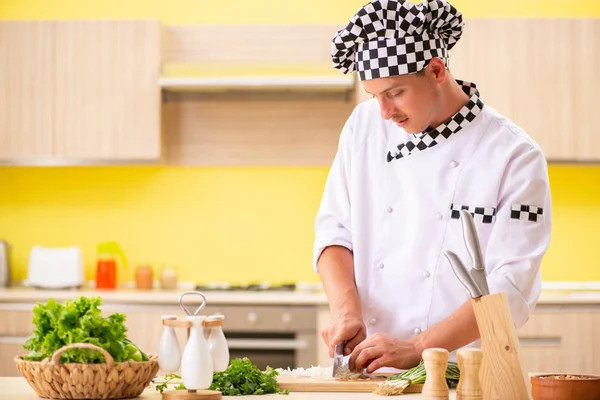 Joven cocinero profesional preparando ensalada en la cocina — Foto de Stock