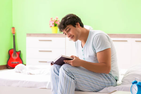 Jovem estudante bonito ler livro na cama — Fotografia de Stock