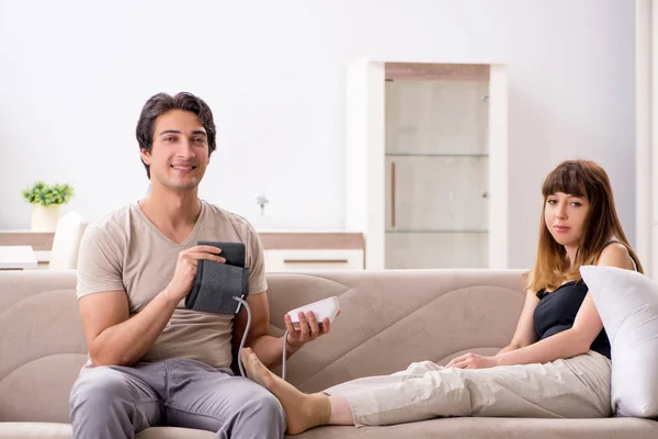 Husband checking wifes blood pressure